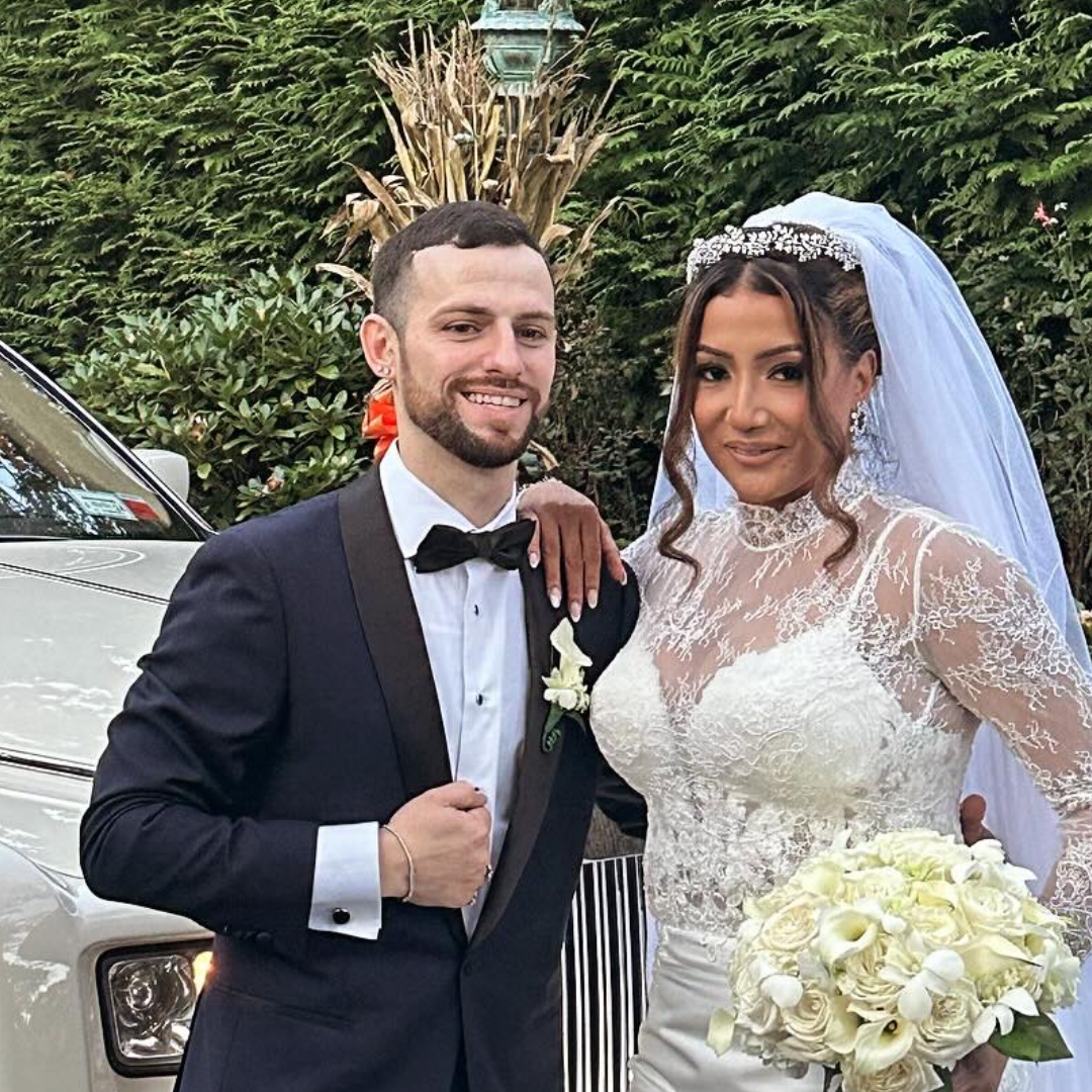 Bride and groom portrait beside a Camelot vehicle